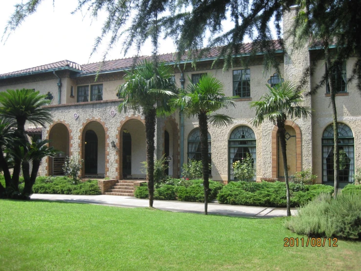 a large house with a beautiful lawn and many palm trees