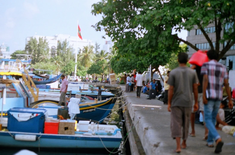 a group of people walking around a harbor filled with small boats