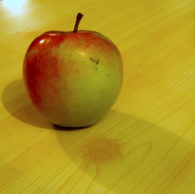 a green apple on the surface of a table