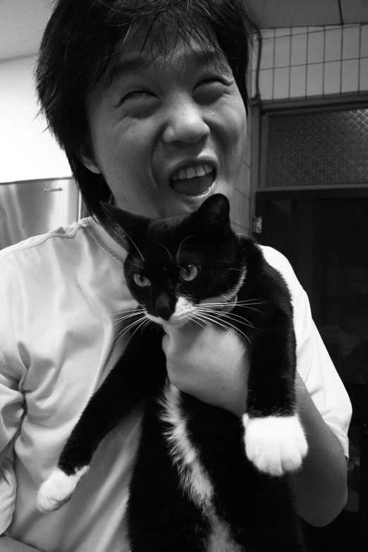 a person holds a black and white cat