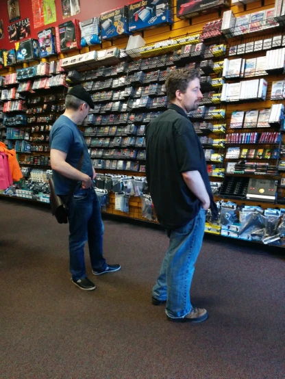 two men stand in a store with electronics