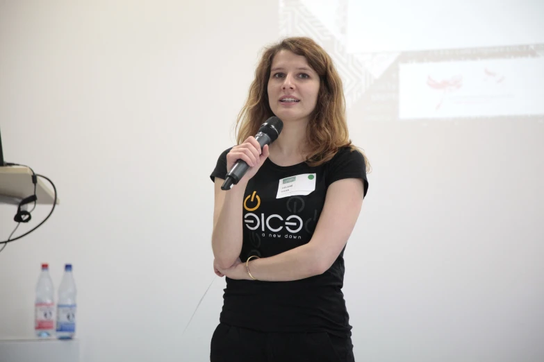 a woman in black shirt and pants standing by a microphone