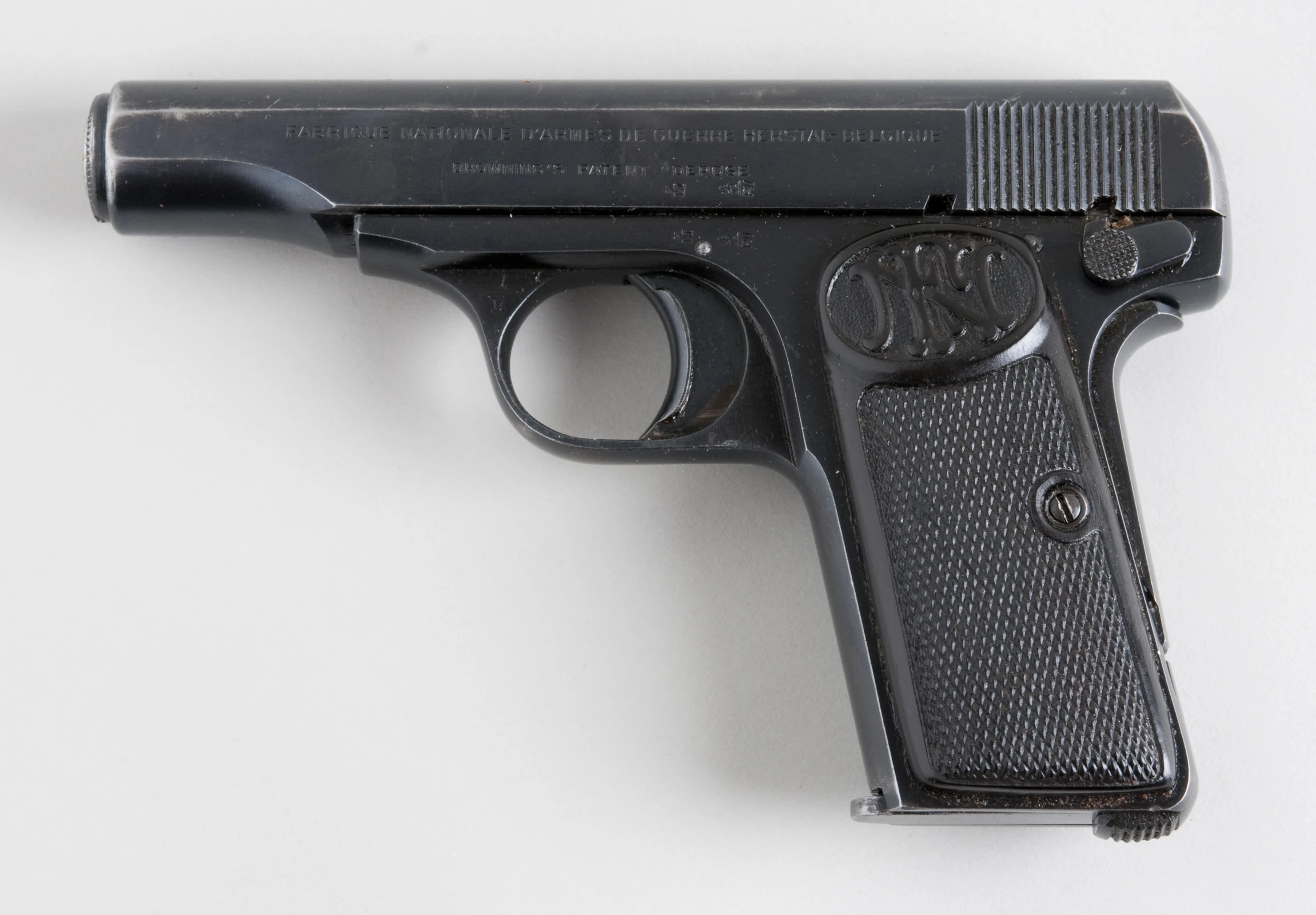 a black gun lying on the floor next to a white background