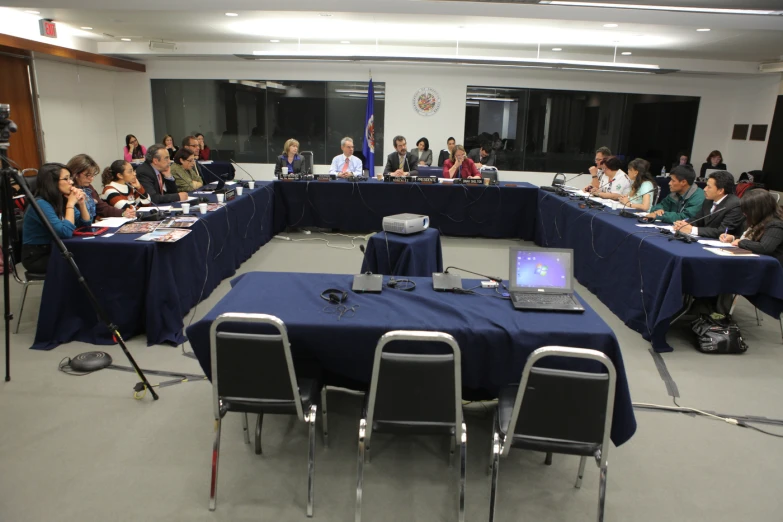 the group of people in the conference room are sitting at tables with laptops