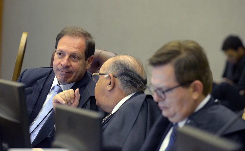 several men sit at tables in front of computers