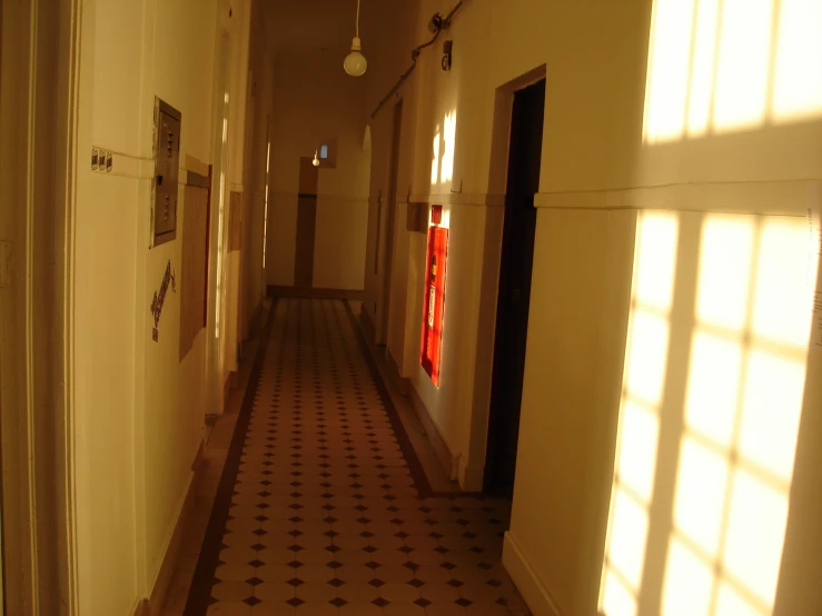 a long narrow hallway with a black and white floor and two windows