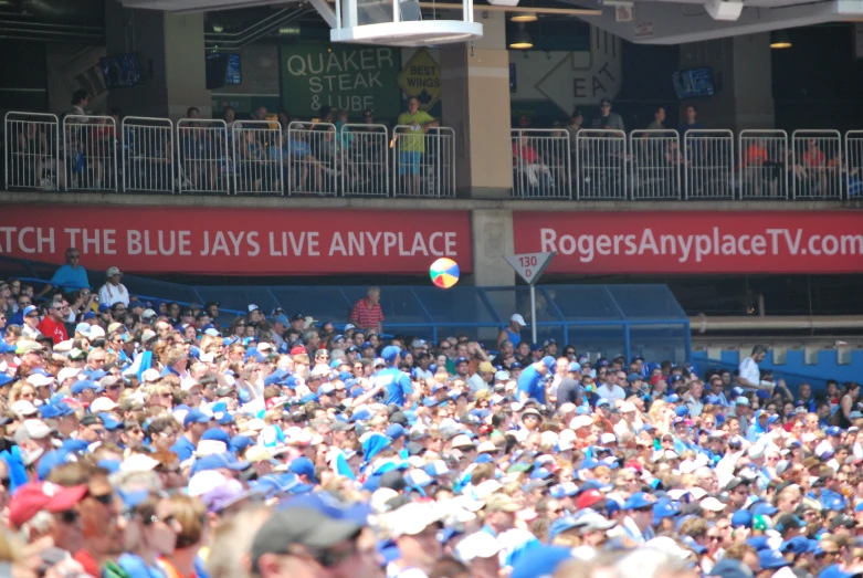 the crowd watches as a blue jayy reaches up to catch the ball