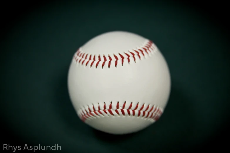 a baseball that is sitting on a dark green surface