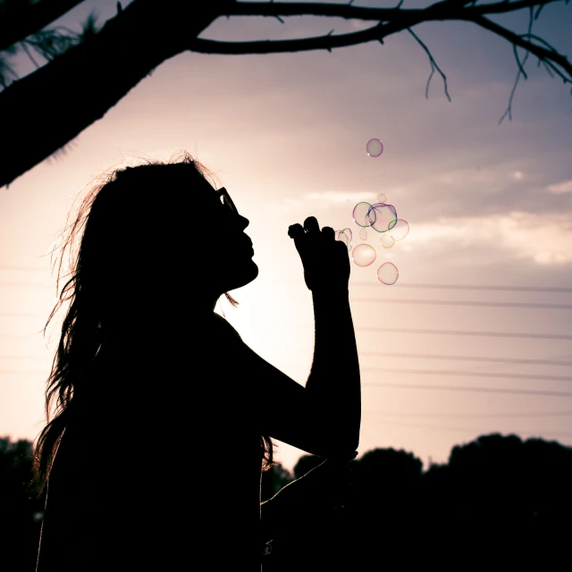 a person standing in a field blowing bubbles