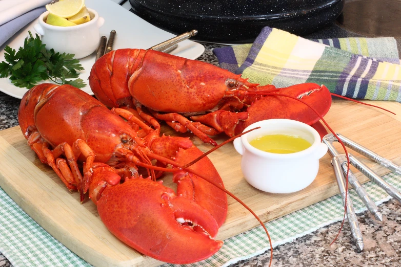 a large cooked lobster sits on a wooden board