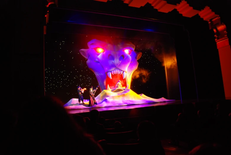 people standing on the stage with a large purple monster projected on it