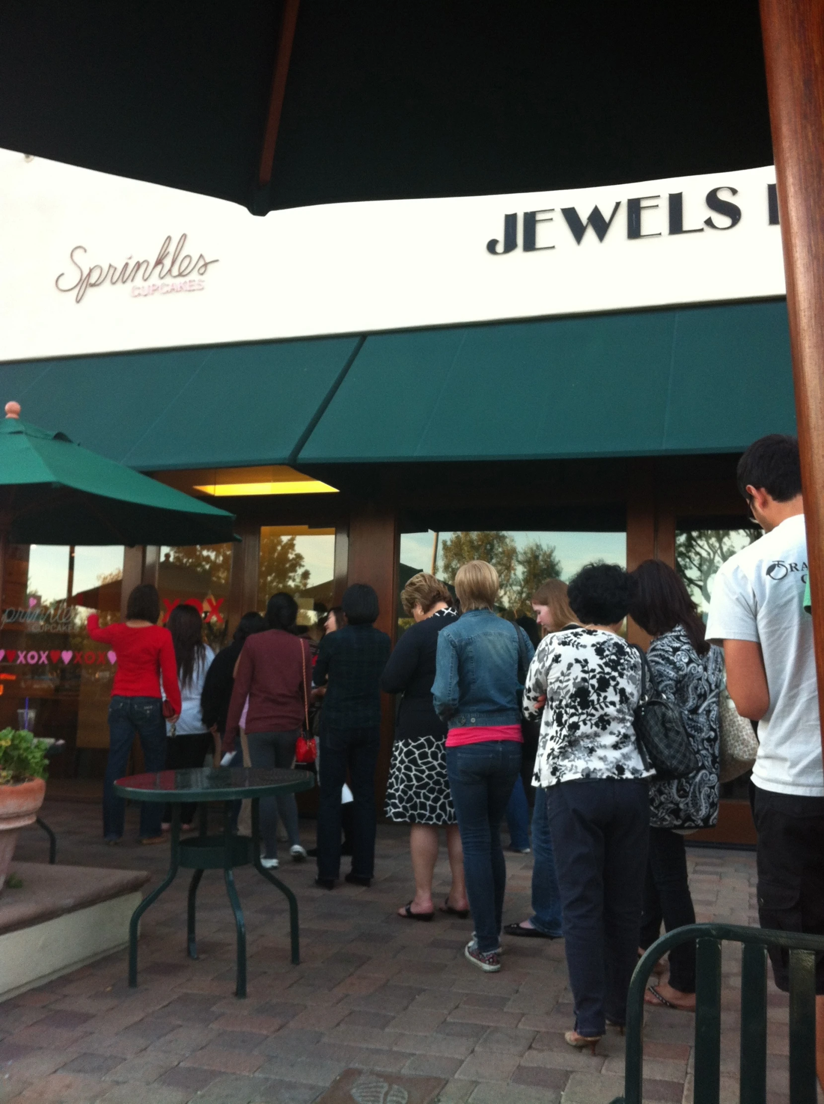 a group of people stand outside of a jewelry store