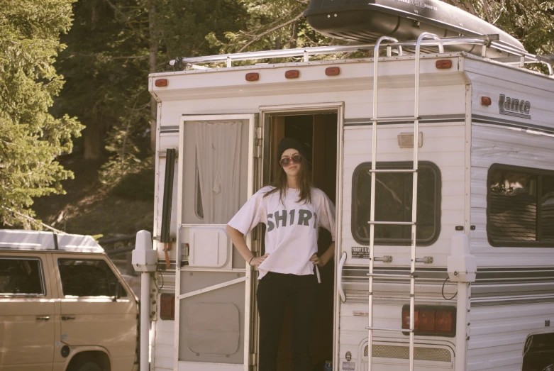 woman in sunglasses and a white shirt stands in an rv doorway