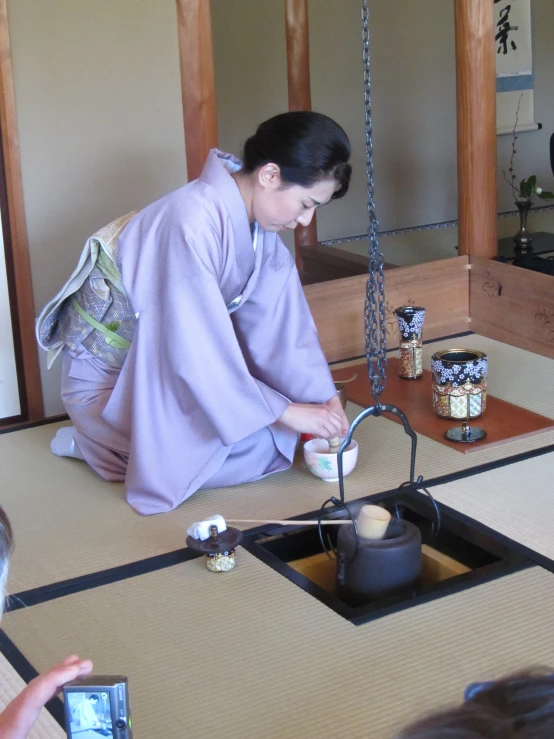 a woman in an oriental geisha kimono painting an object