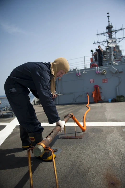 a sailor is inspecting a broken pipe on the ship