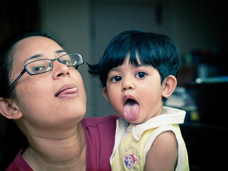 a woman with glasses is looking at a baby's tongue