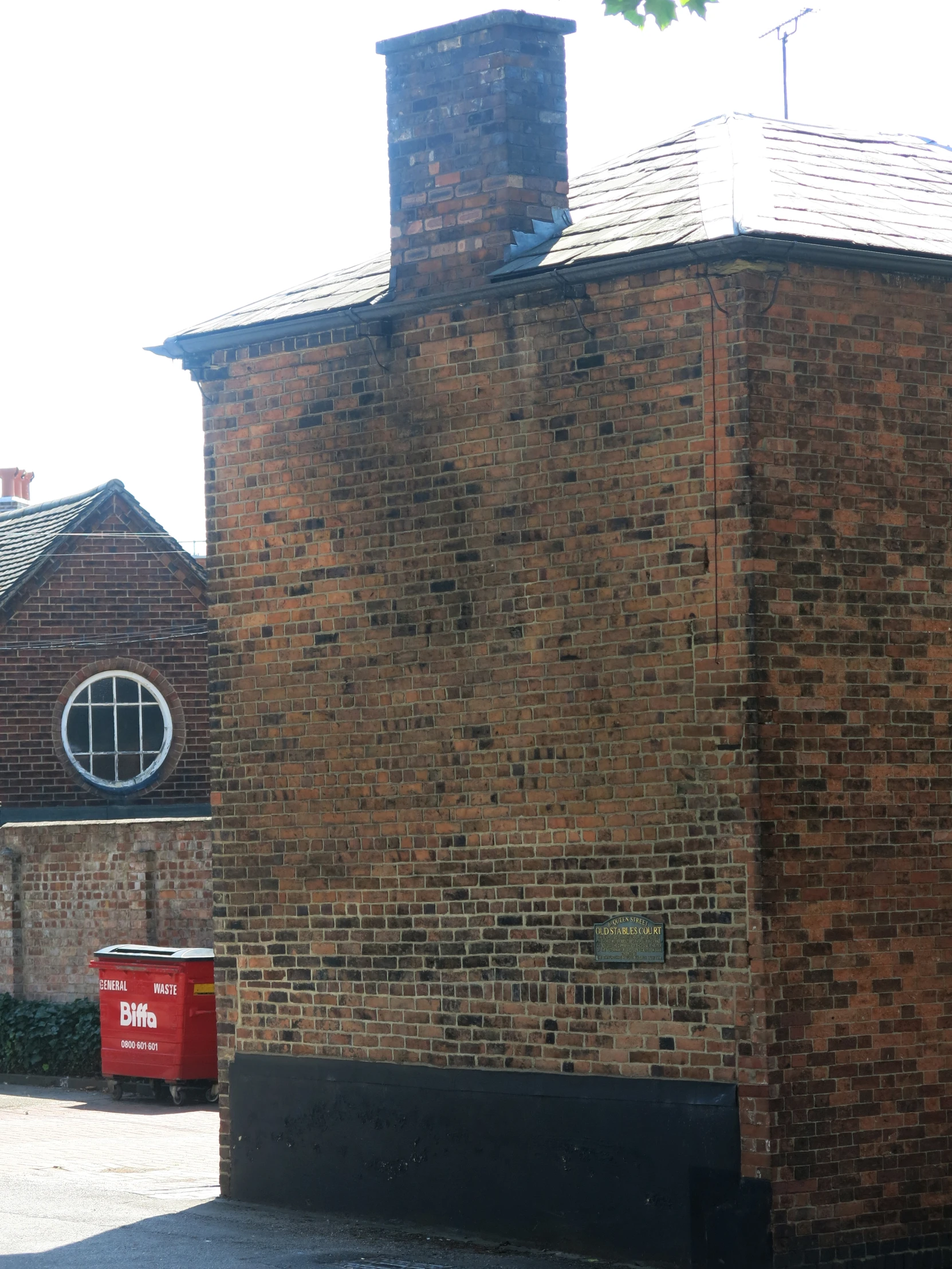 there is a red trash can in front of this brick building