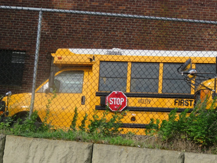 there is a yellow bus behind a chain link fence