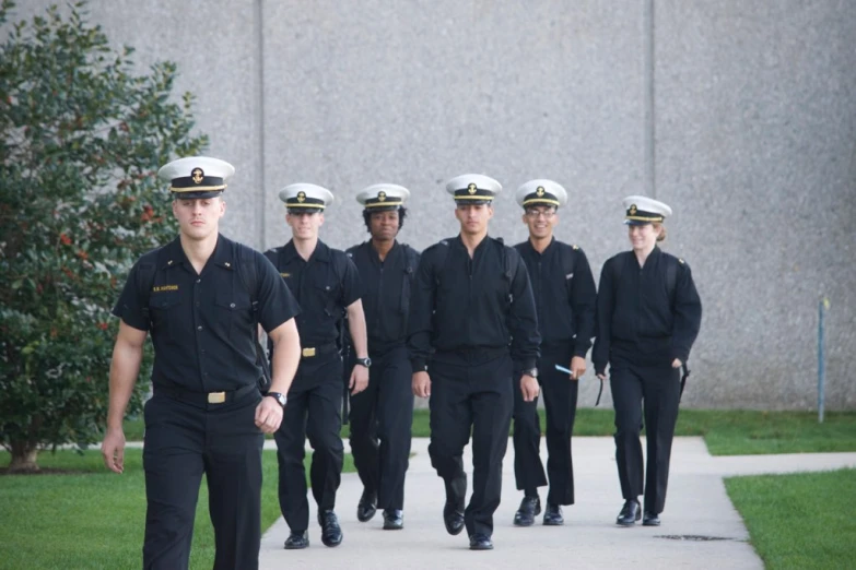 a group of sailors in a group walking through a park