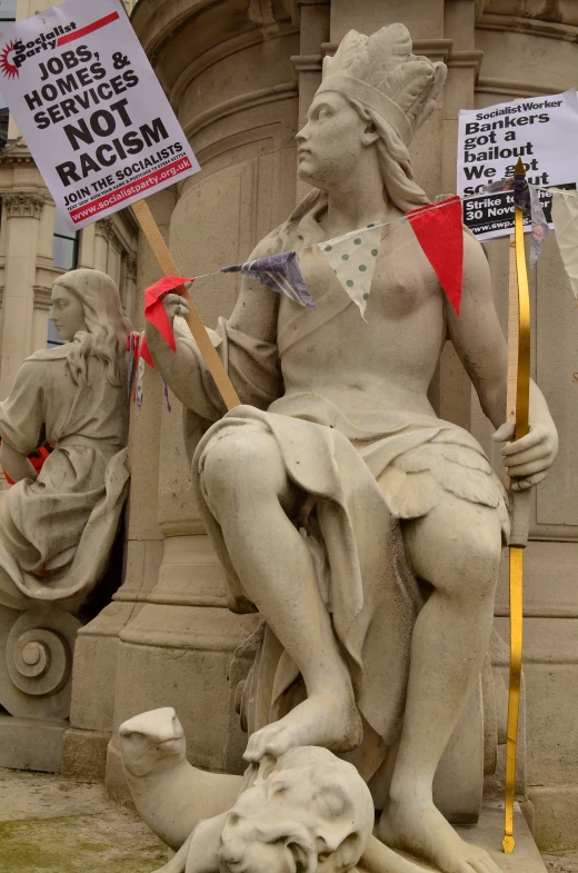 a statue with protest signs on its arms