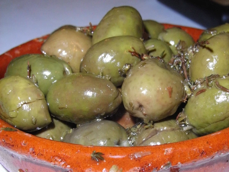 an orange bowl filled with a bunch of green olives