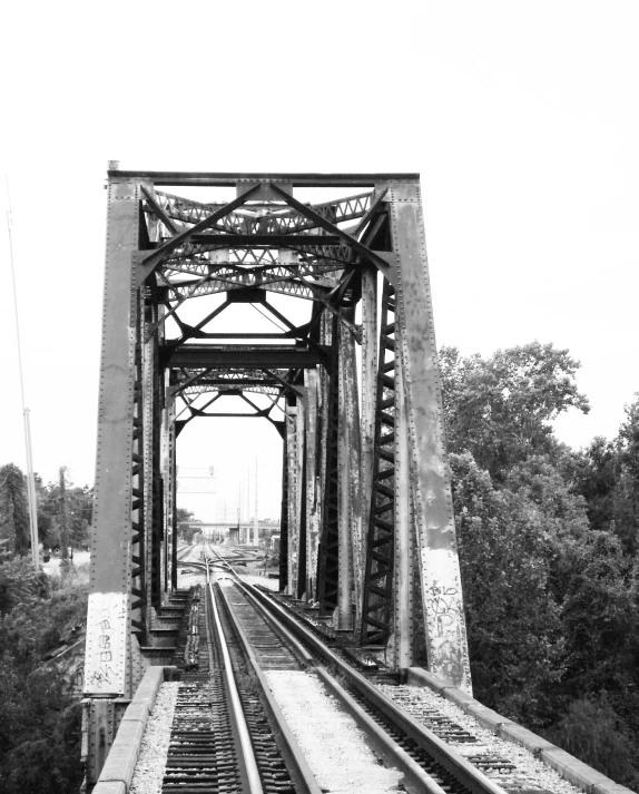 a black and white picture of the tracks leading to the bridge