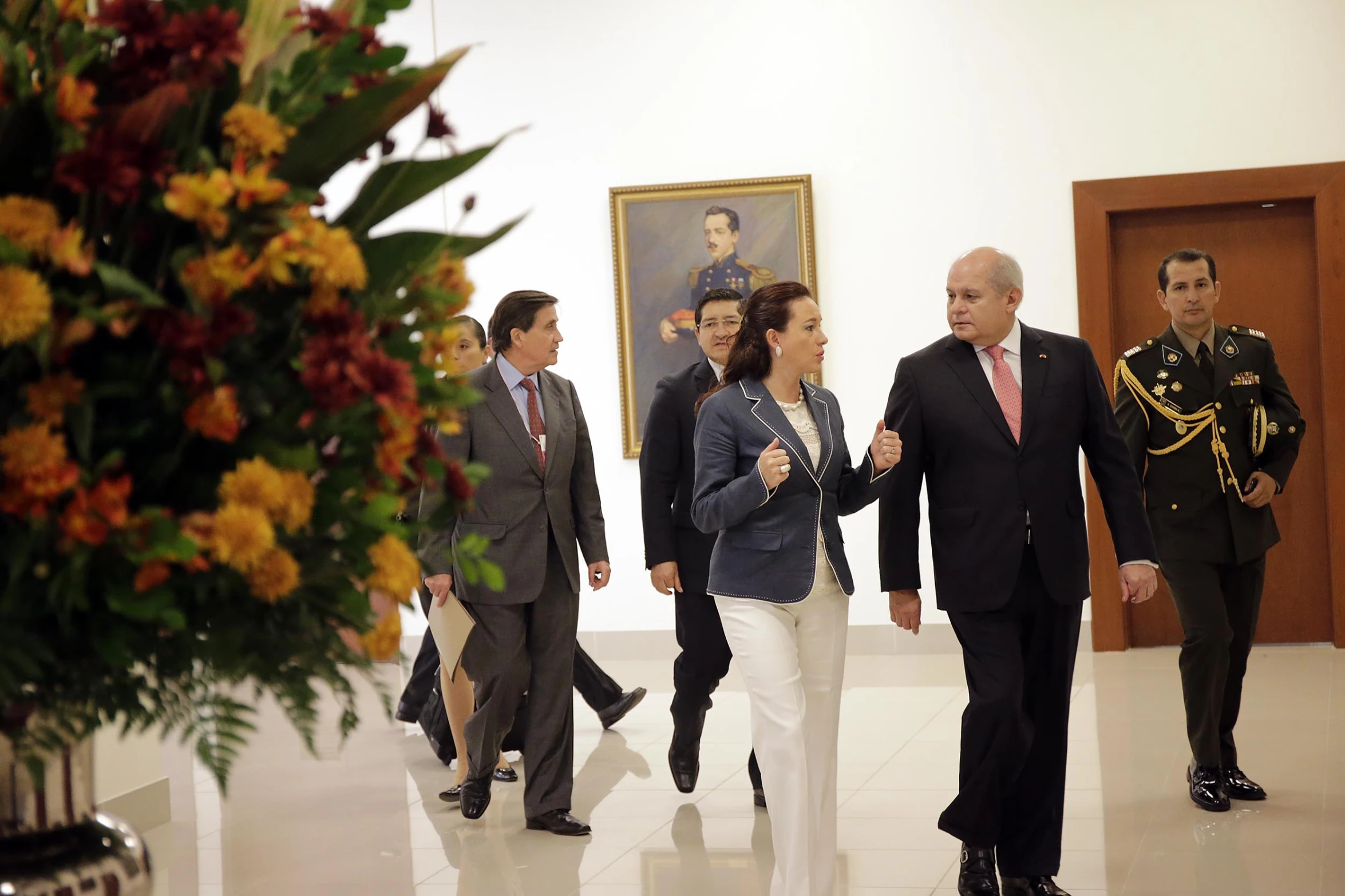 a man walks with two women in uniform while other men stand next to him