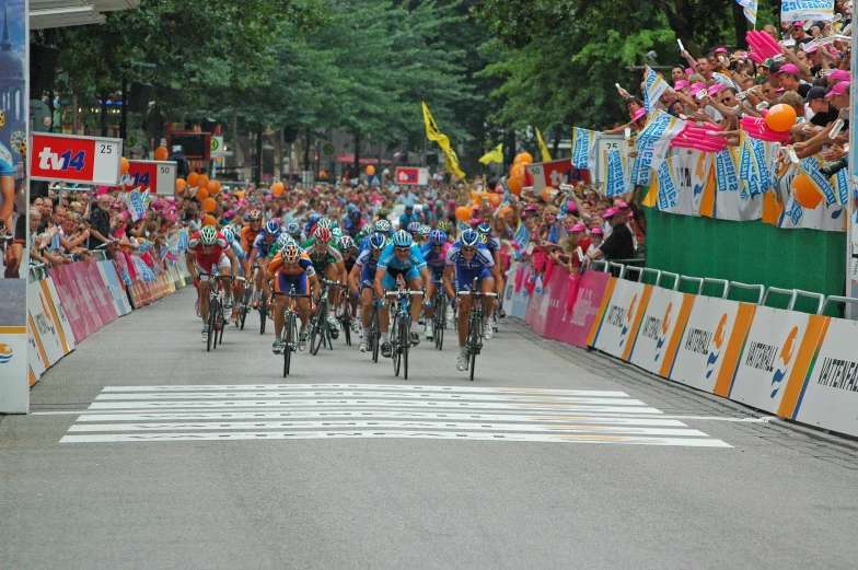 professional cyclists ride their bikes on the street with crowd watching
