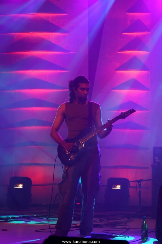 a man with his guitar standing in the middle of the stage