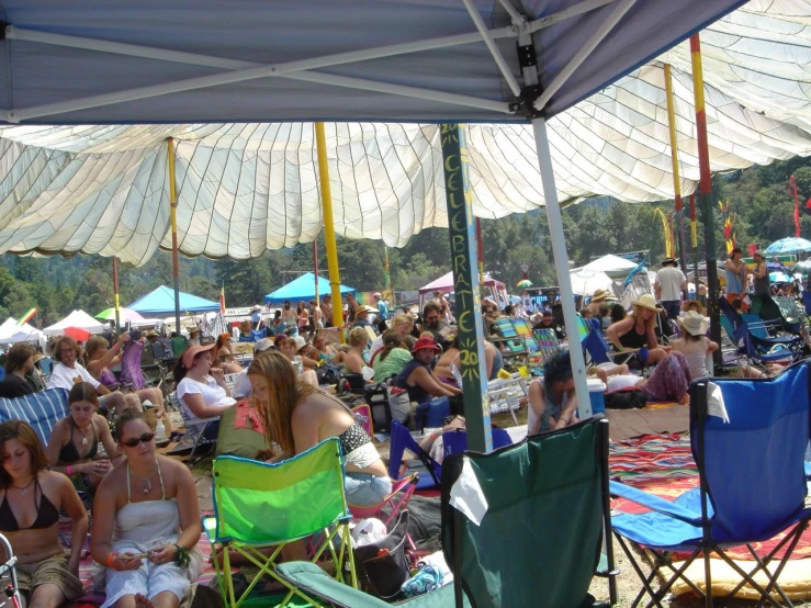 an outdoor gathering with many people sitting under some tents