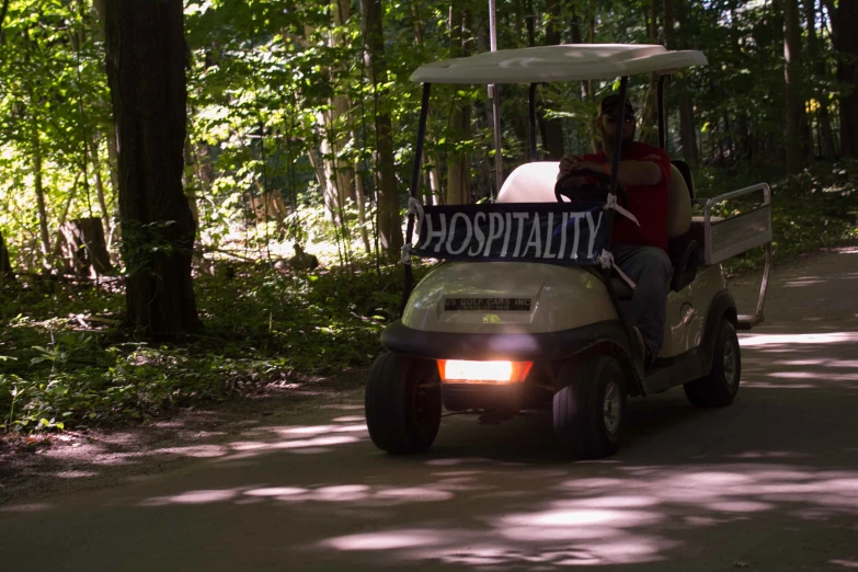 a golf cart carrying two people in a wooded area