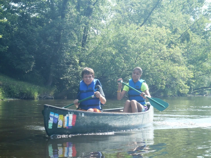 two young people rowing a canoe on the water