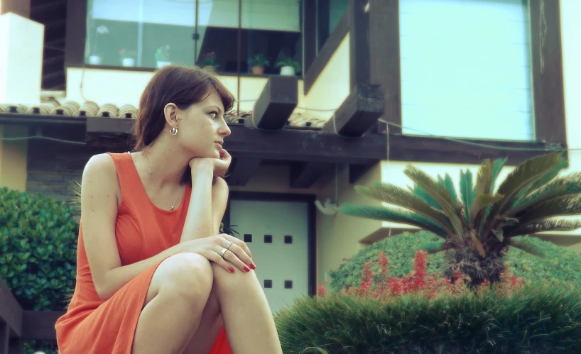 a woman sits on the ground near a building