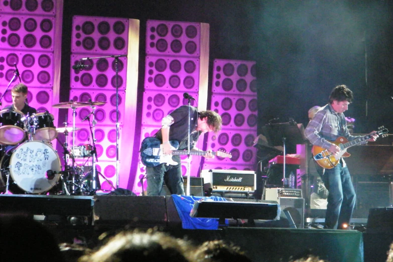 a band plays music on stage in front of a purple screen