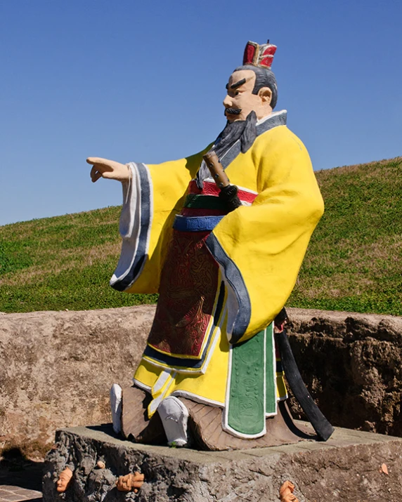 a statue of a man dressed in japanese clothing holding an arm out