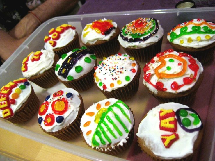 cupcakes decorated with multicolored frosting in a plastic box