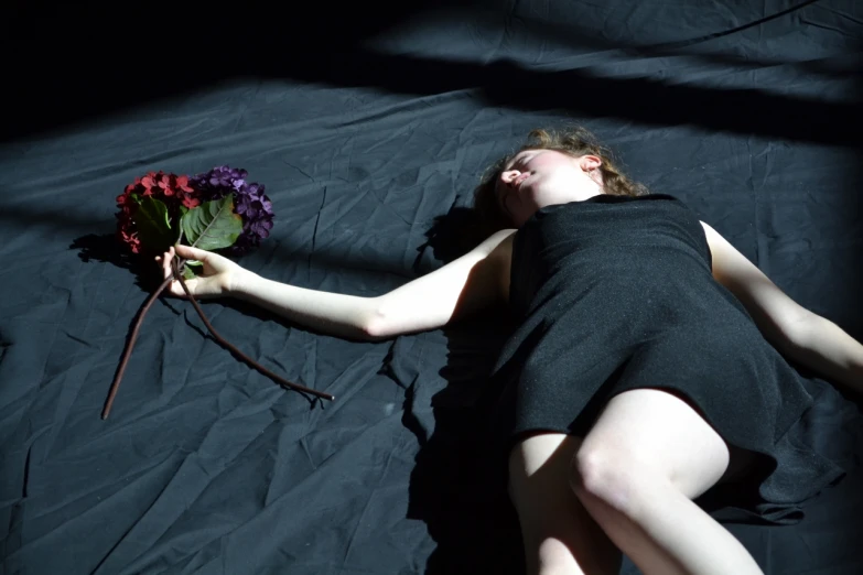 a beautiful young woman laying down in bed with a bouquet of flowers