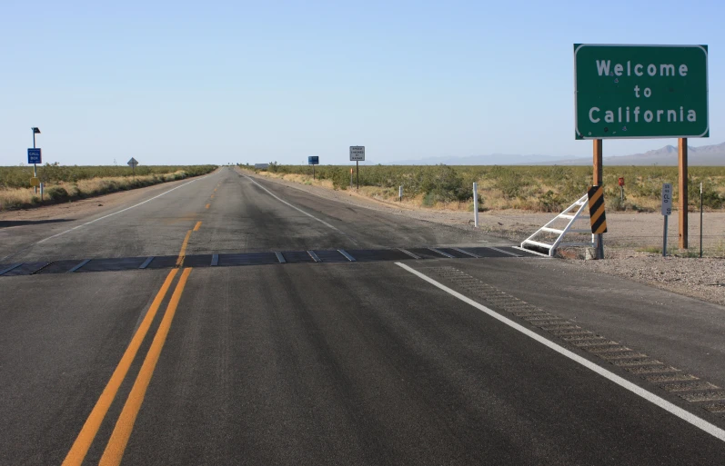 a view of a road that has a welcome to california sign on it