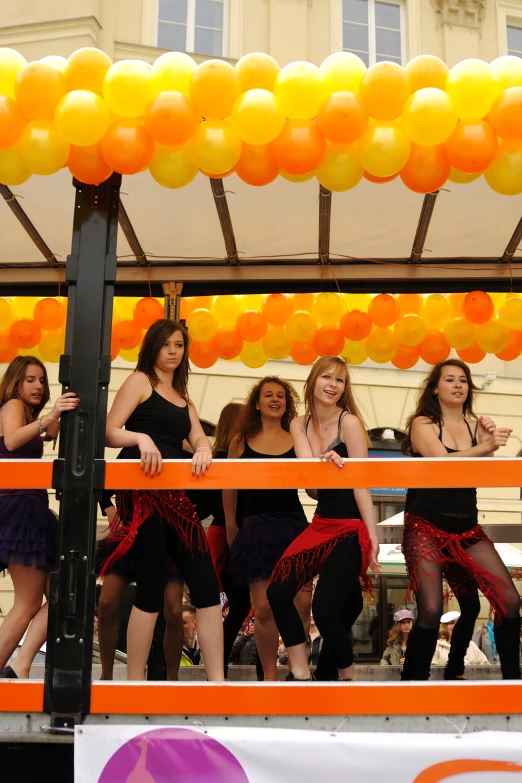 a group of women in dance poses under balloons