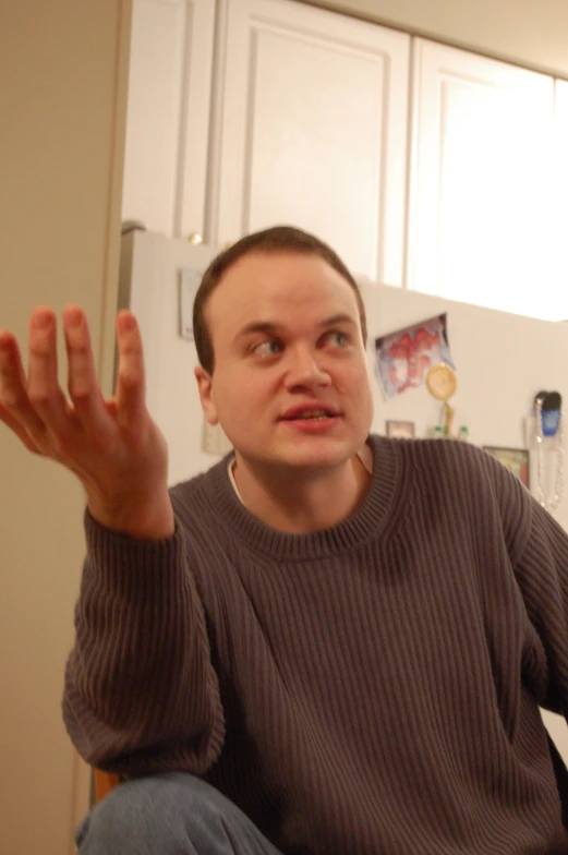 a man holding his hand up while standing in a kitchen