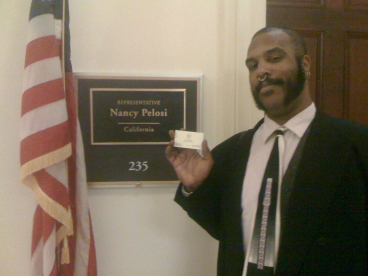 man standing in front of flags holding up card