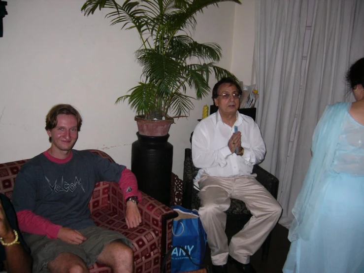 a man in black shirt sitting next to a woman on red couch