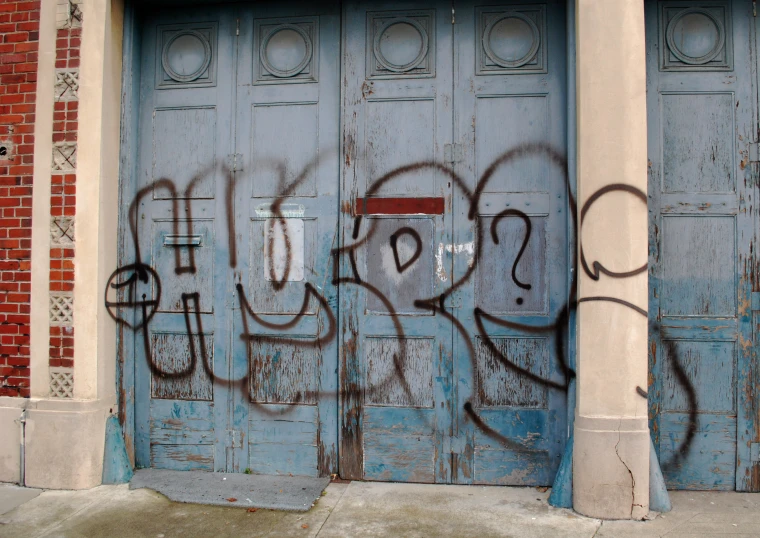 graffiti is spray painted on a door as the street is quiet