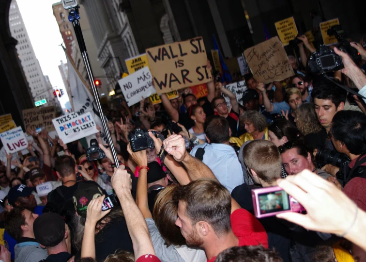 many people holding up signs and cell phones while walking down the street