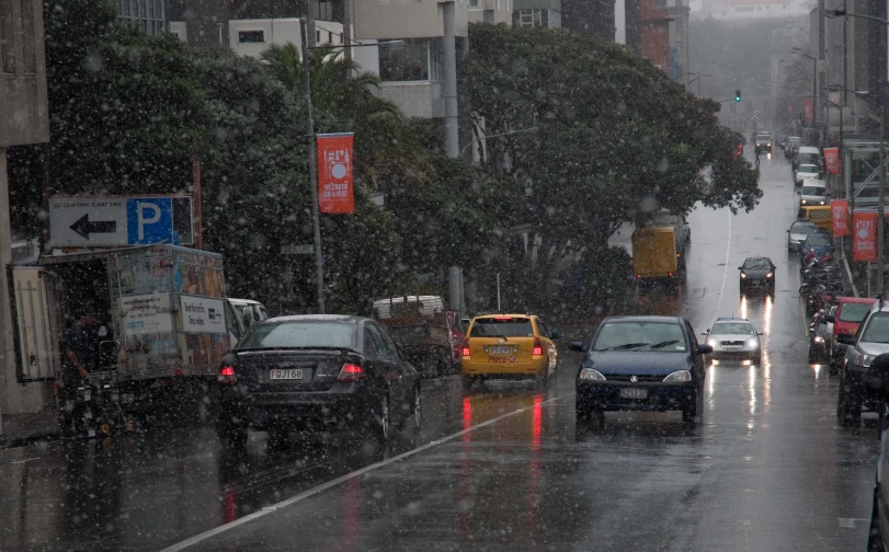 several cars are driving on a wet city street