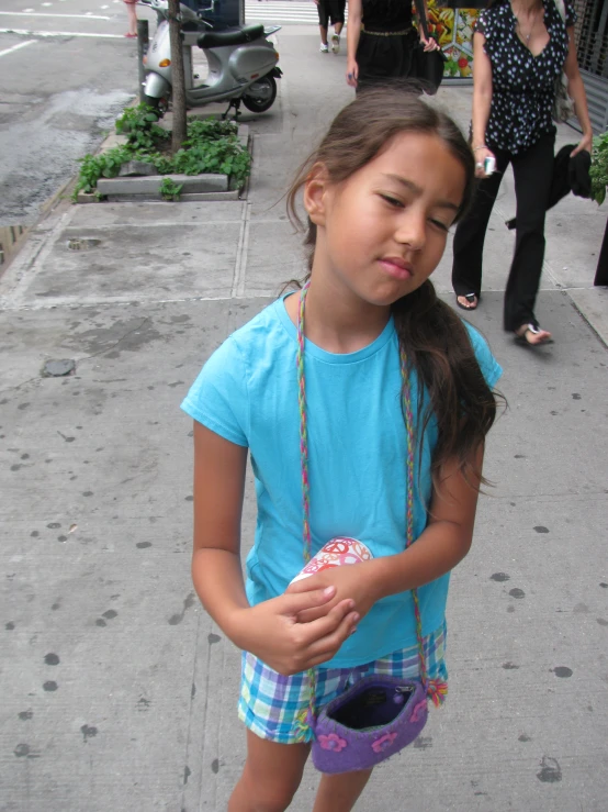 a girl standing on the sidewalk holding a plastic object