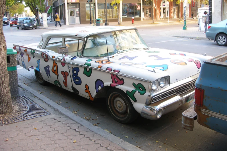 a car painted in many colors parked by the side of the street