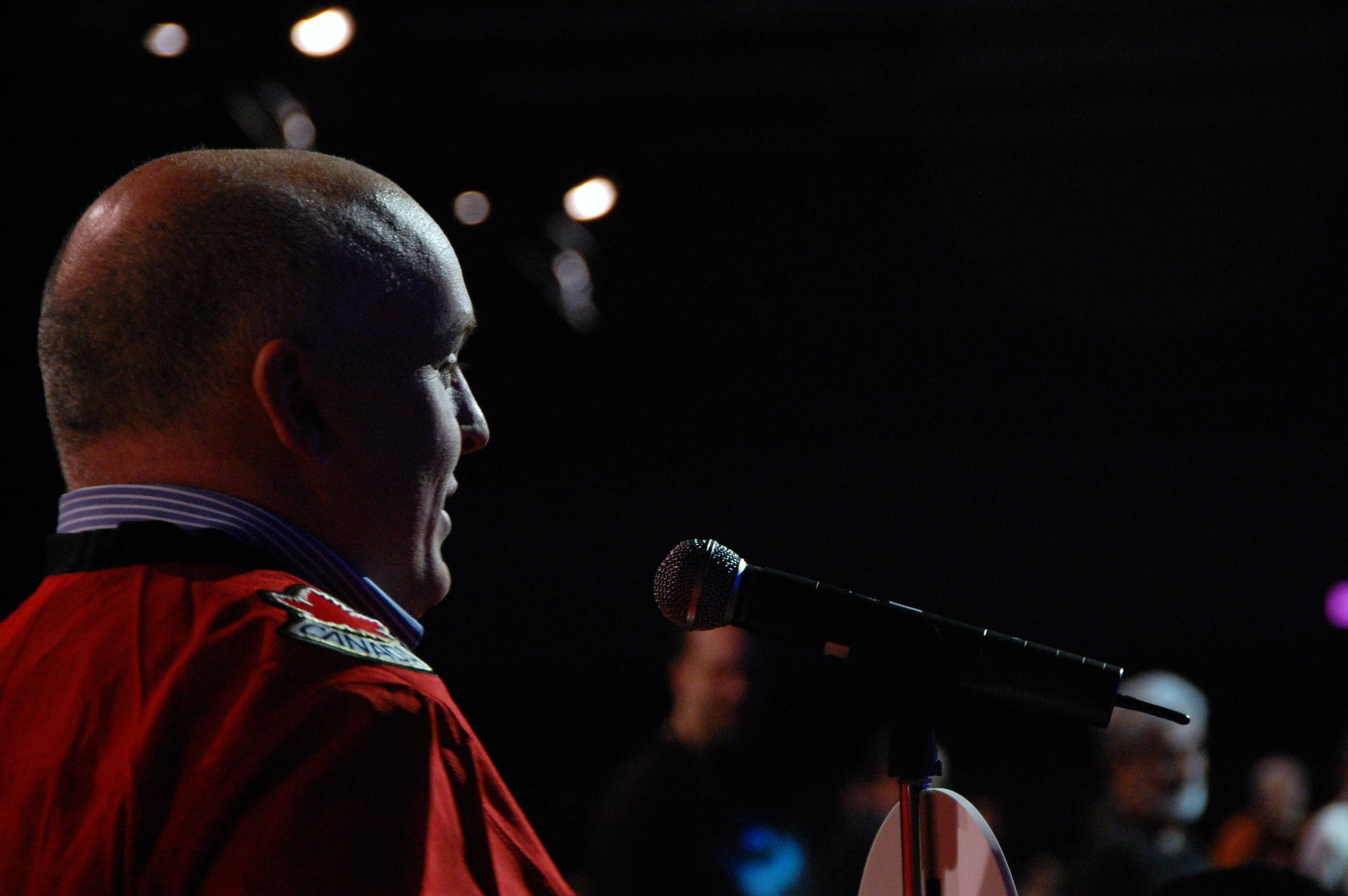 a man with a red vest talking into a microphone
