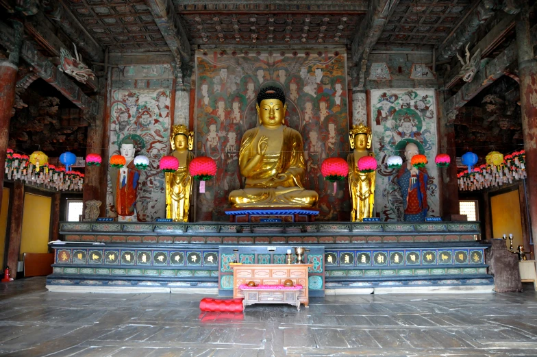 the person is sitting at a bench under a golden statue