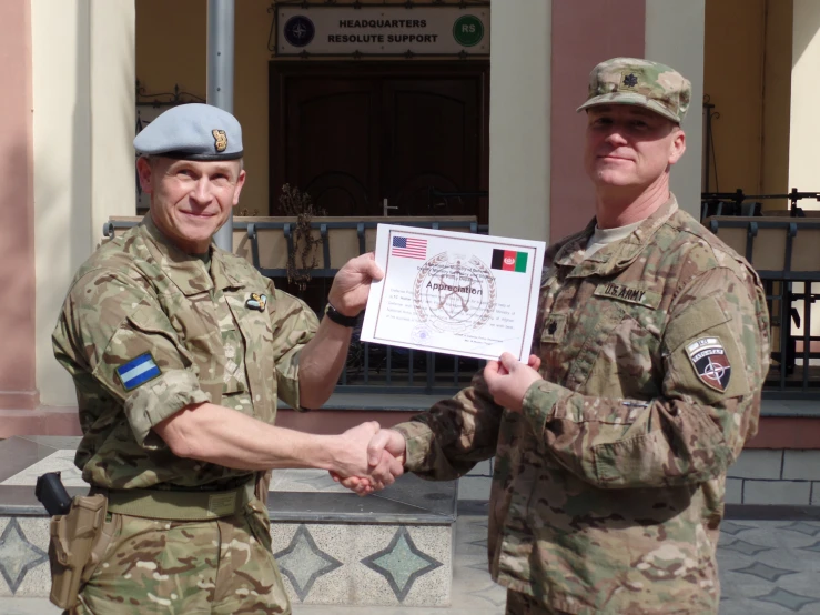 two military men shaking hands in front of an building